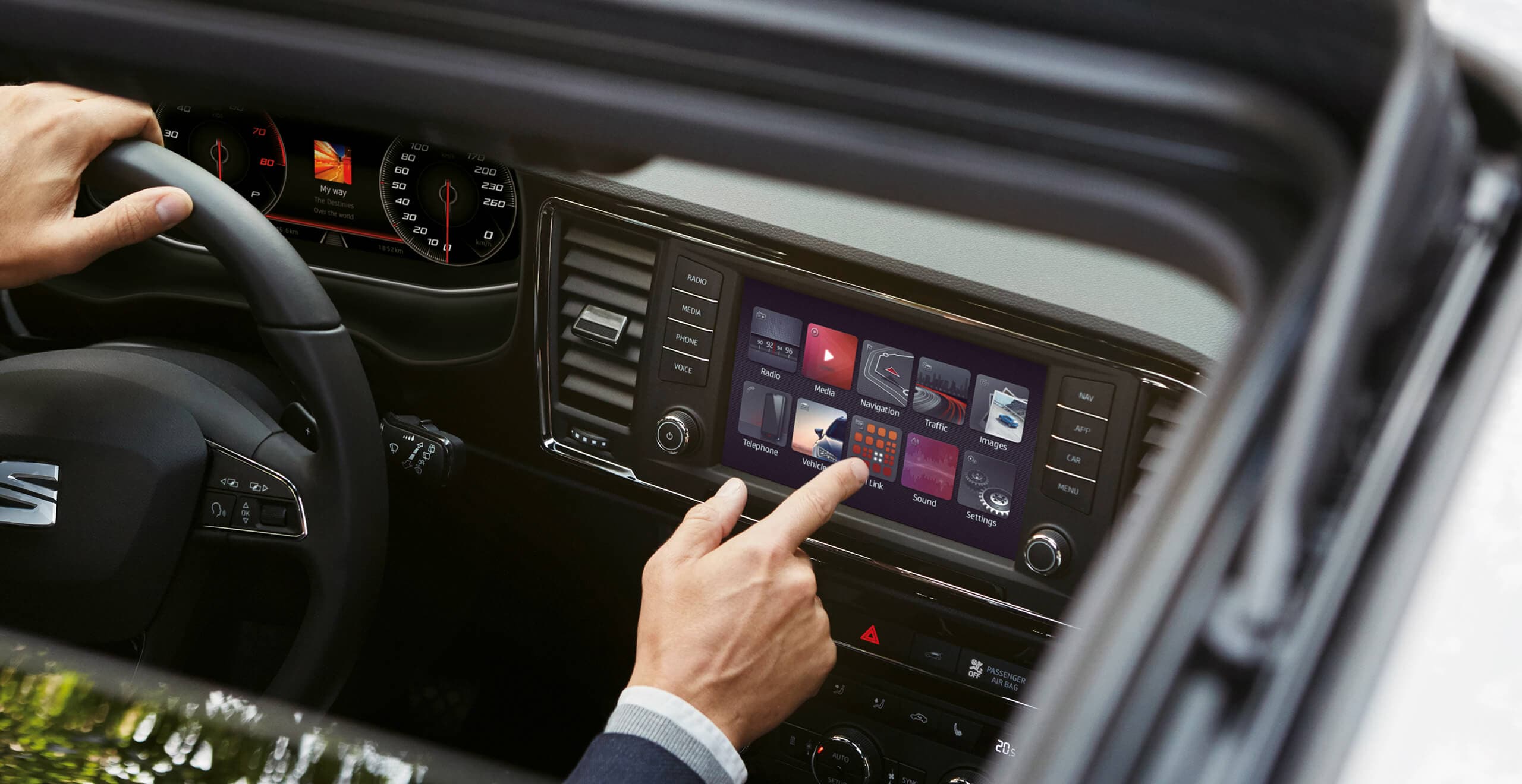 a man at the steering wheel of a SEAT pointing to the dashboard screen