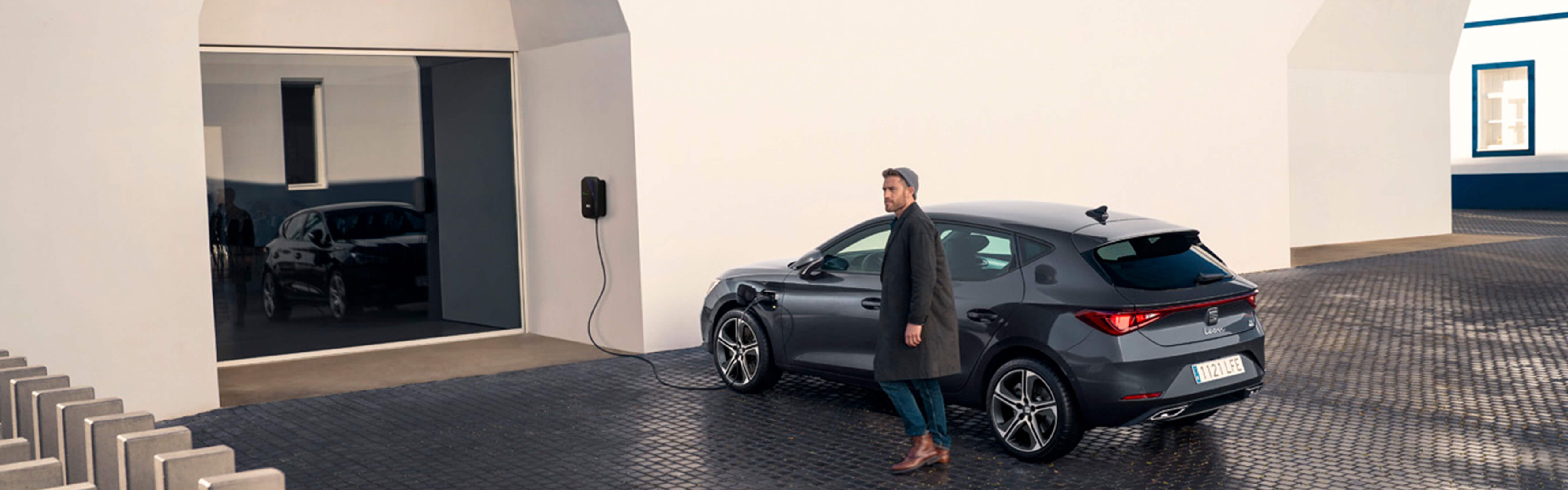 Man walking away from SEAT Leon e-HYBRID whilst on his phone.